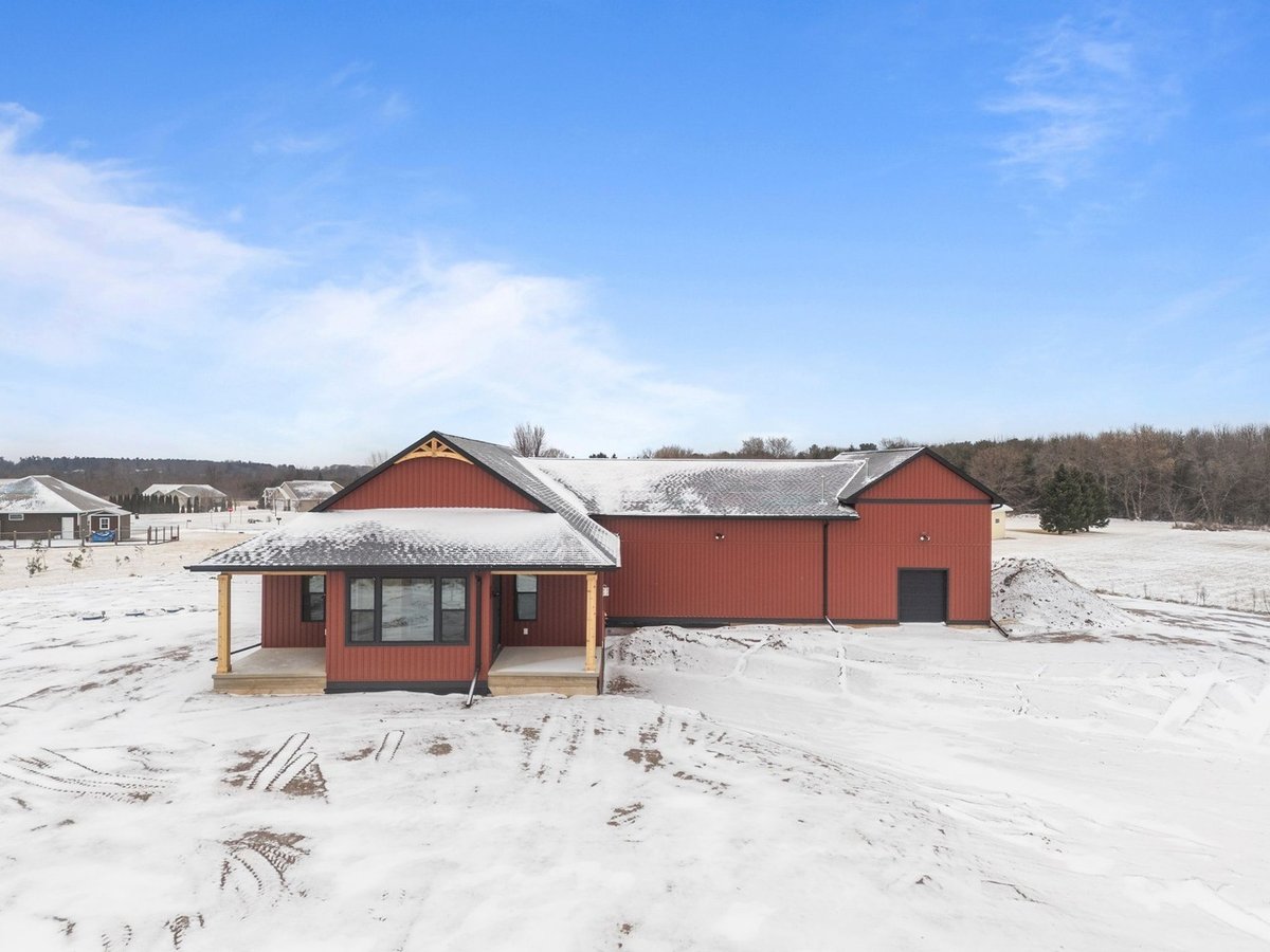 Back view of red custom home with snow by Midwest Design Homes in Wisconsin