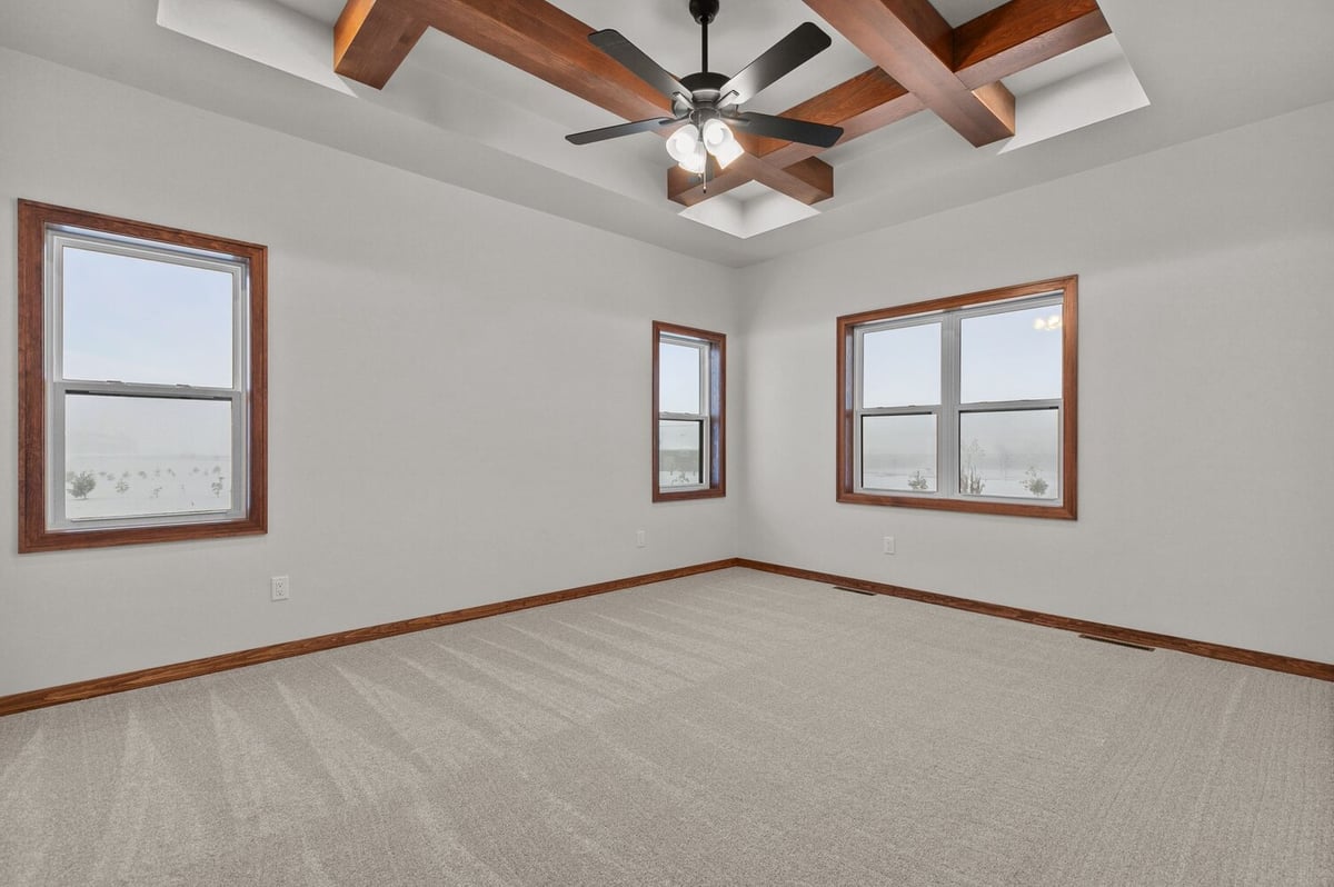 Bedroom with tray ceiling and fan in custom Kaukauna, WI home by Midwest Design Homes