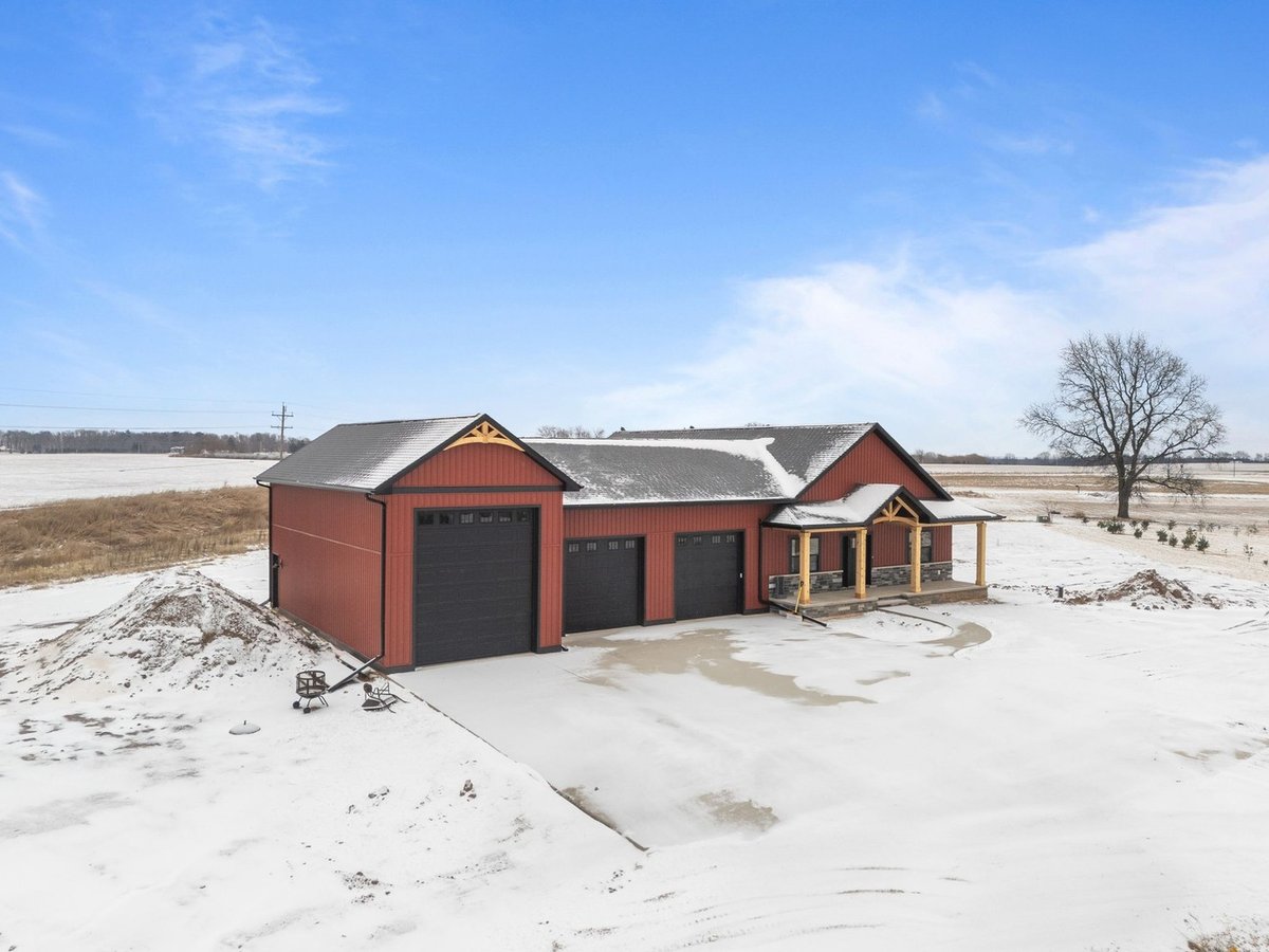 Black garage doors on red custom home in snowy Kaukauna by Midwest Design Homes