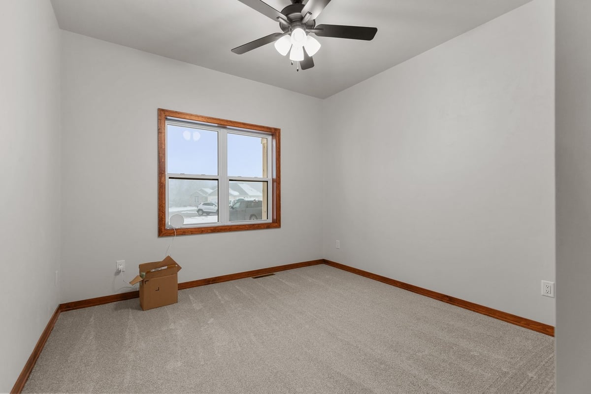 Carpeted bedroom with large window in Kaukauna, WI custom home by Midwest Design Homes