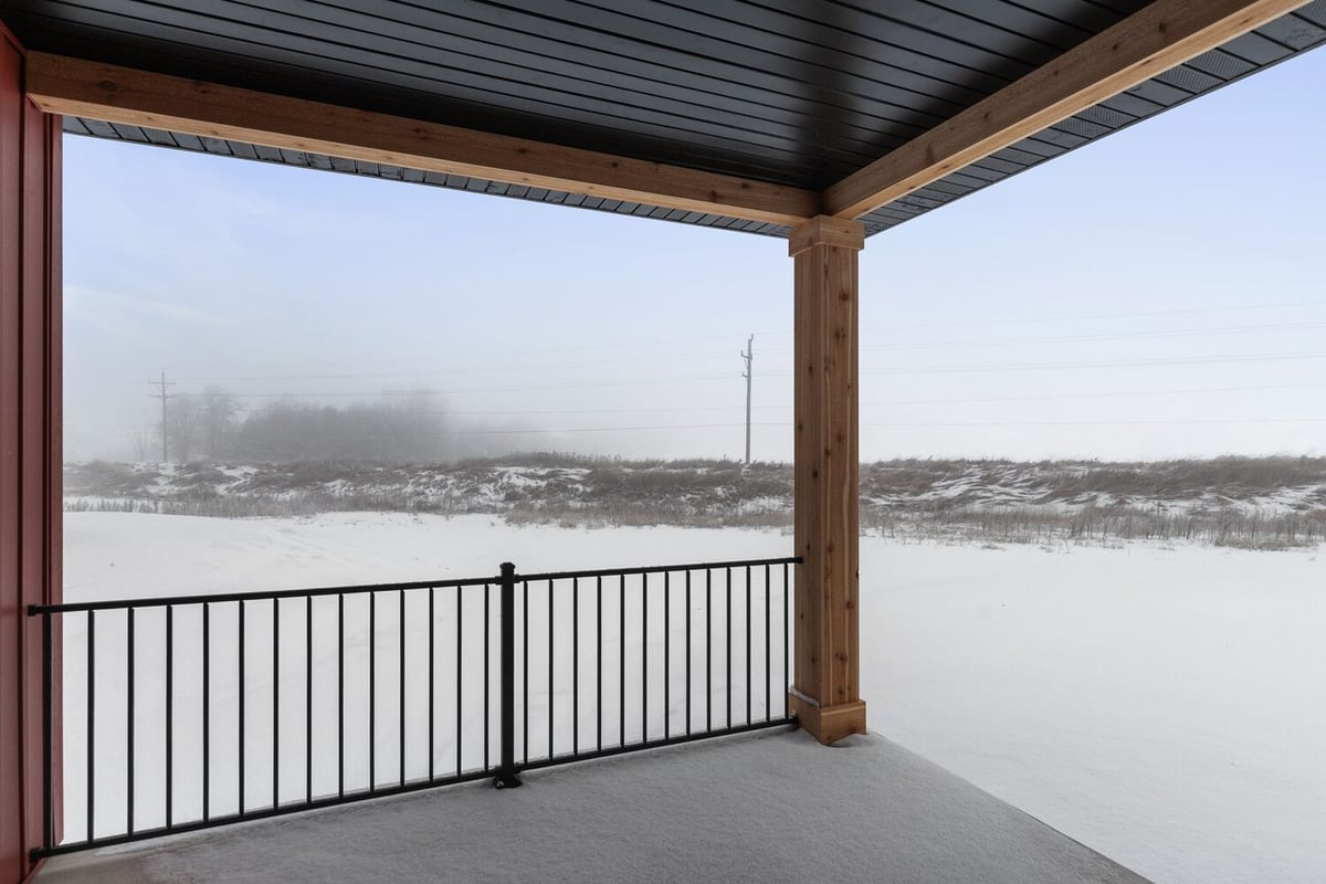 Custom home back porch with railing in snowy Kaukauna landscape by Midwest Design Homes