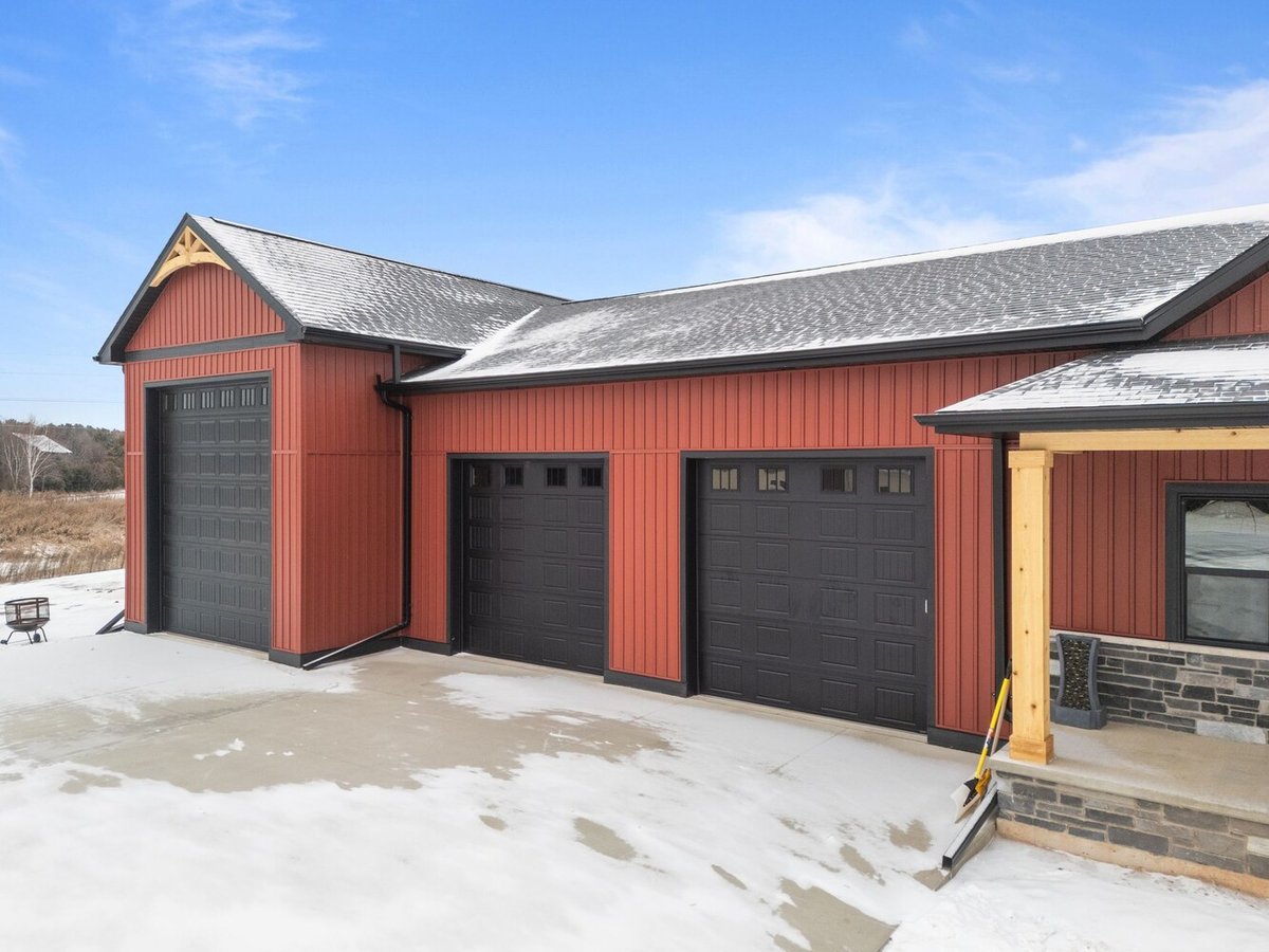 Custom home garage with stone pillars in snowy Kaukauna, WI by Midwest Design Homes