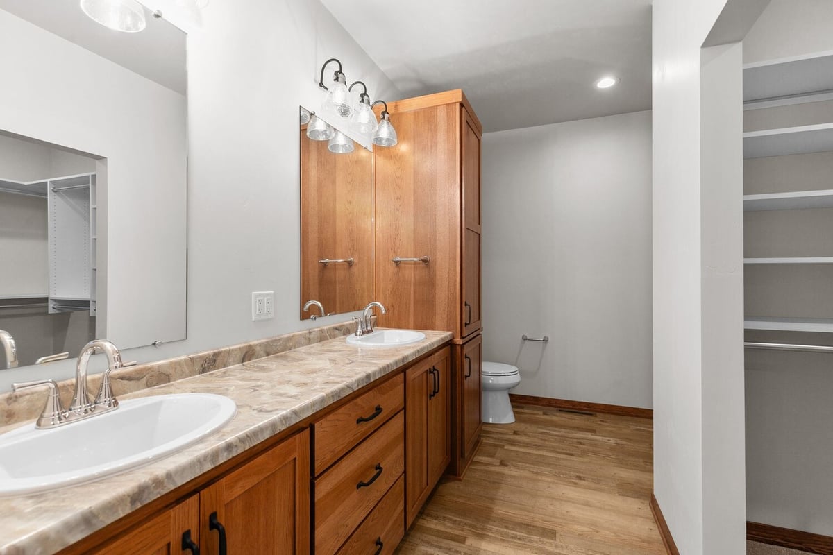 Dual vanity and wood cabinetry bathroom in Kaukauna home by Midwest Design Homes