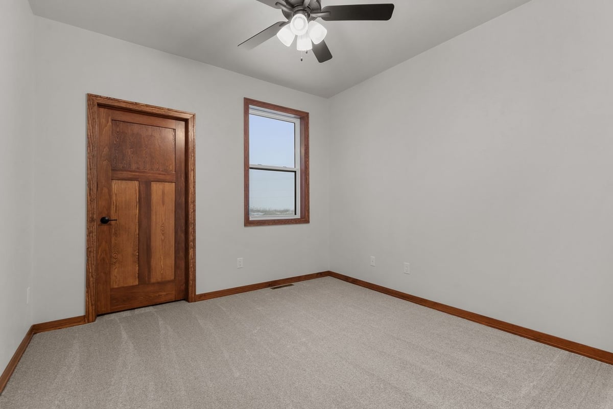 Guest bedroom with wood door in Kaukauna, WI custom home by Midwest Design Homes