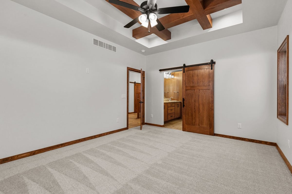 Master bedroom with ceiling beams and barn doors by Midwest Design Homes, Kaukauna