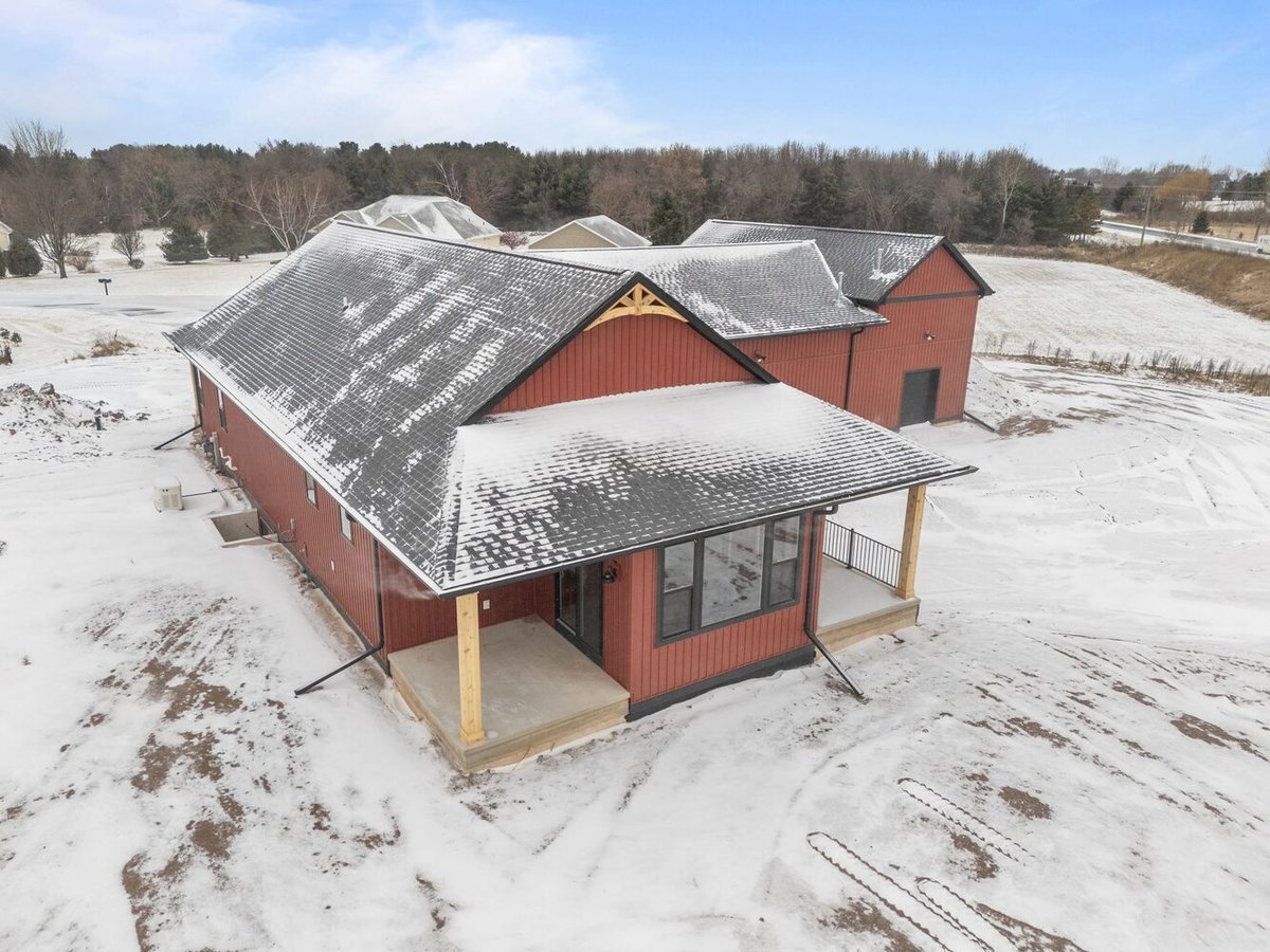 Side view of red custom home with snow in Kaukauna, WI by Midwest Design Homes