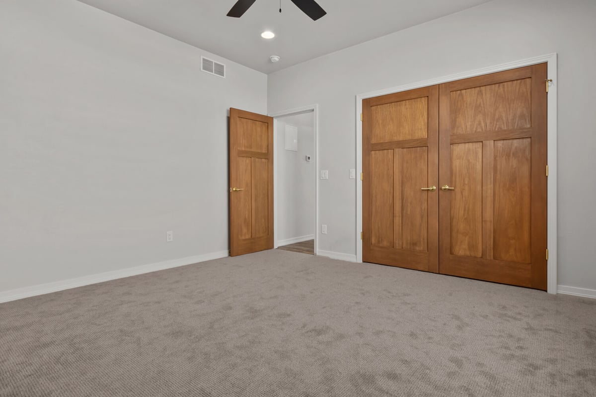 Bedroom with carpet and double door closet by Midwest Design Homes in Kaukauna, WI