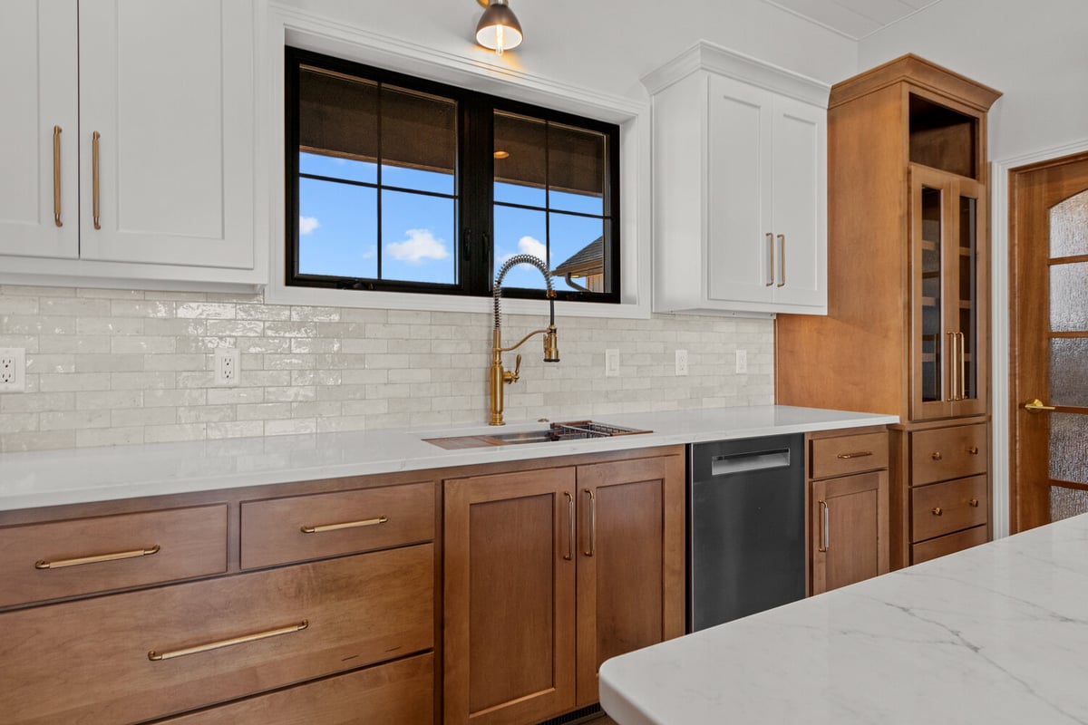 Brass faucet and white tile backsplash in custom home kitchen by Midwest Design Homes WI