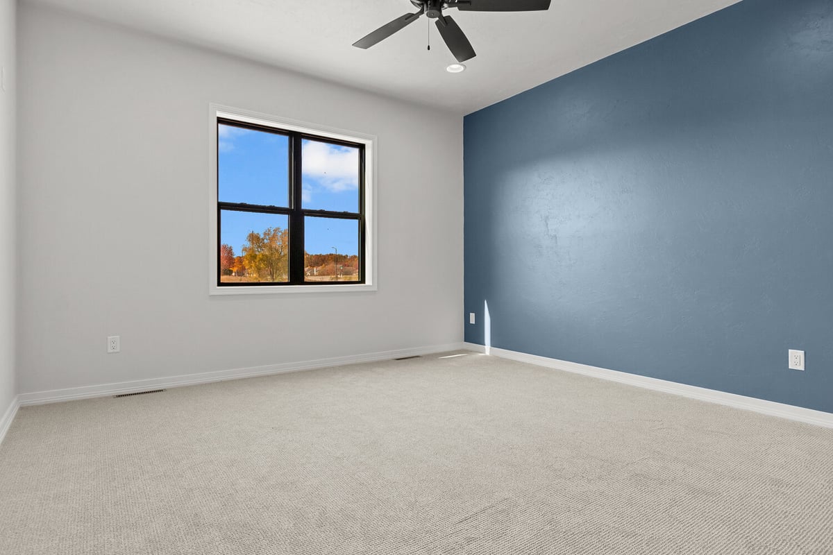Bright bedroom with large window and blue wall by Midwest Design Homes in Neenah, WI