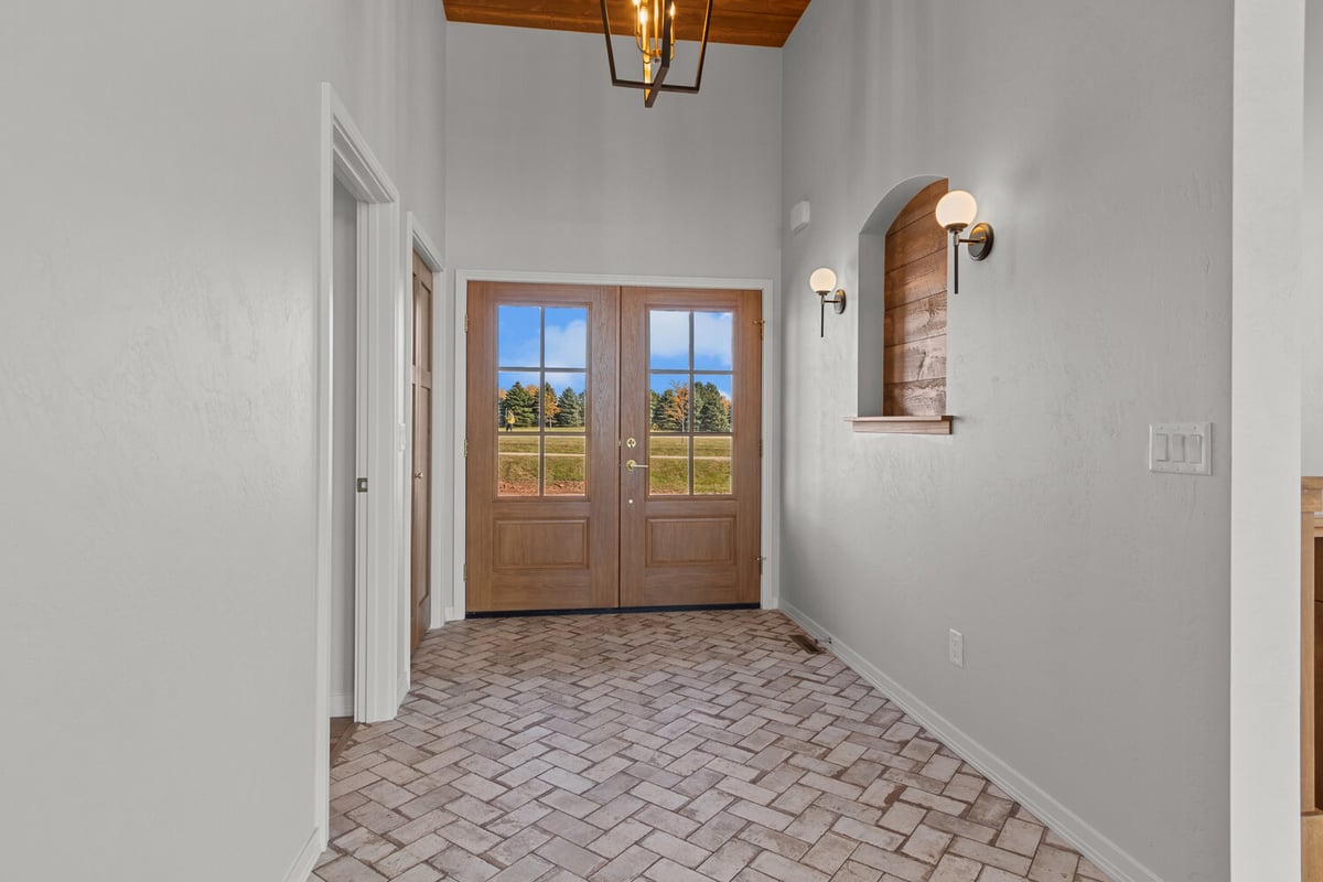 Entryway with herringbone tile and sconce lights by Midwest Design Homes in De Pere, WI