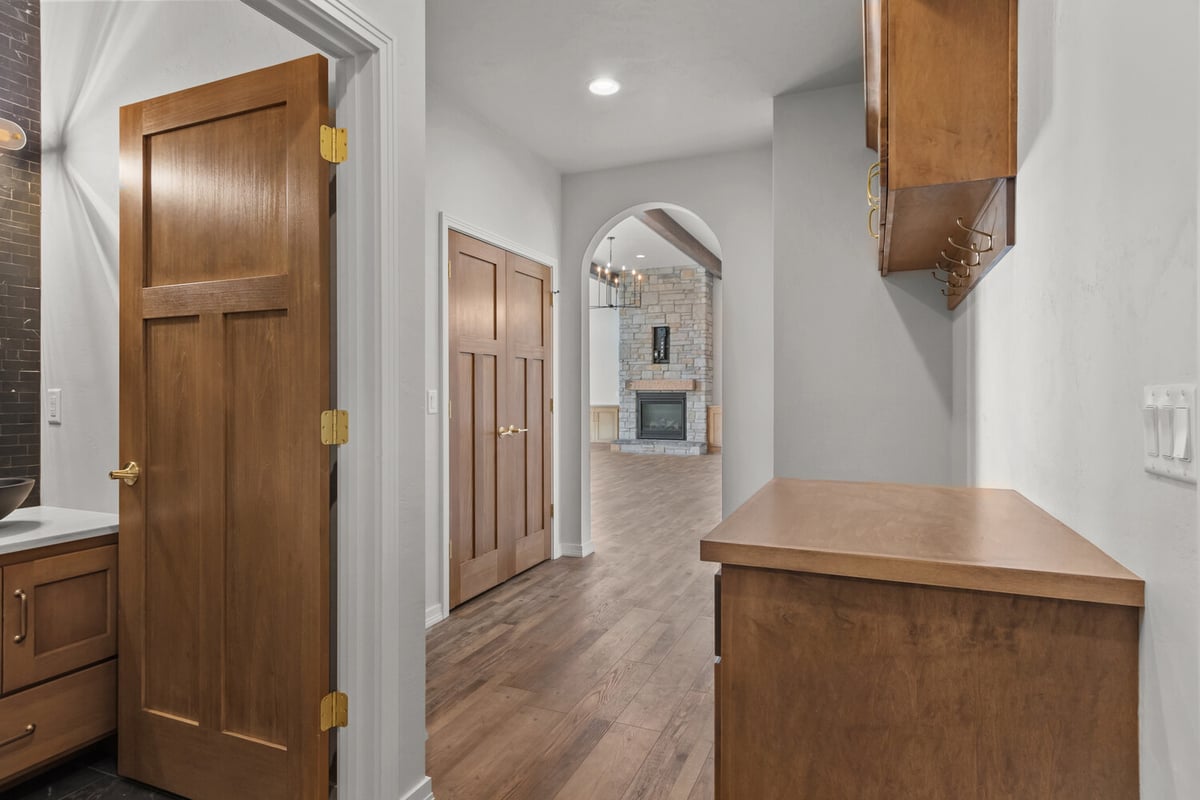 Hallway with arched entry and stone fireplace in Kaukauna home by Midwest Design Homes