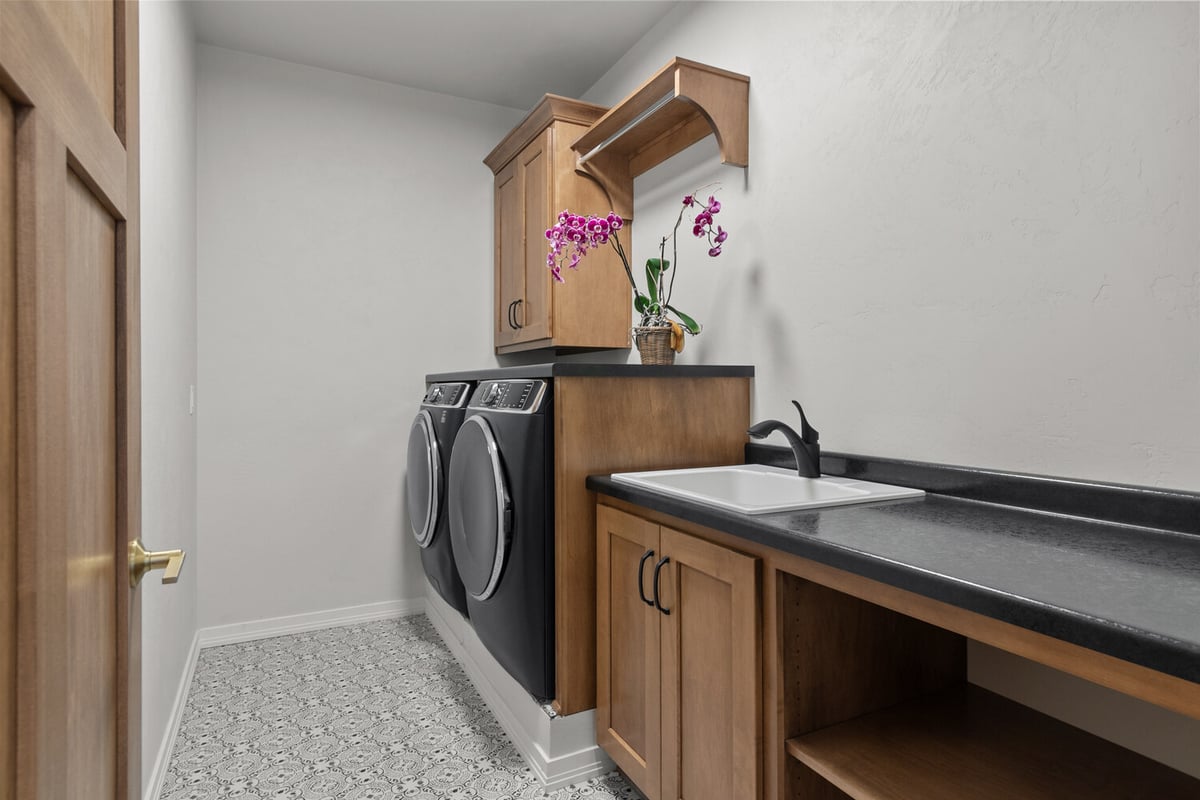 Laundry room with washer, sink, and floral decor by Midwest Design Homes in Kaukauna, WI