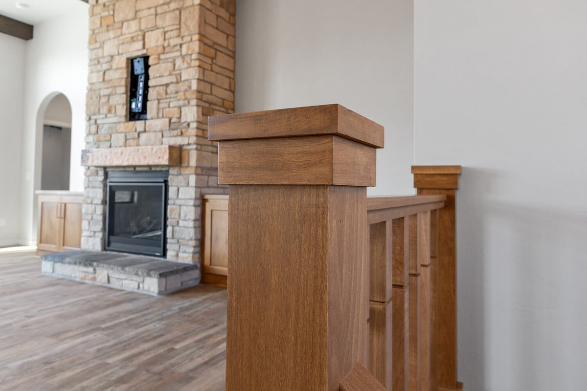 Living room fireplace with wood railing by Midwest Design Homes in Fremont, Wisconsin
