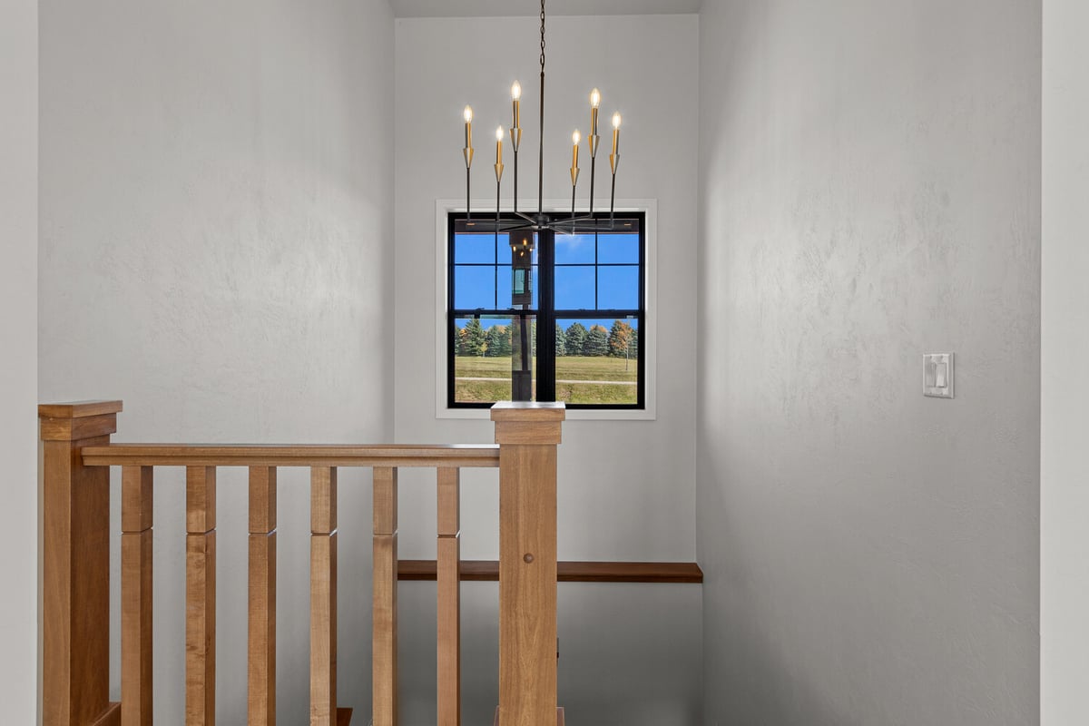 Staircase with chandelier and window view by Midwest Design Homes in Fremont, WI