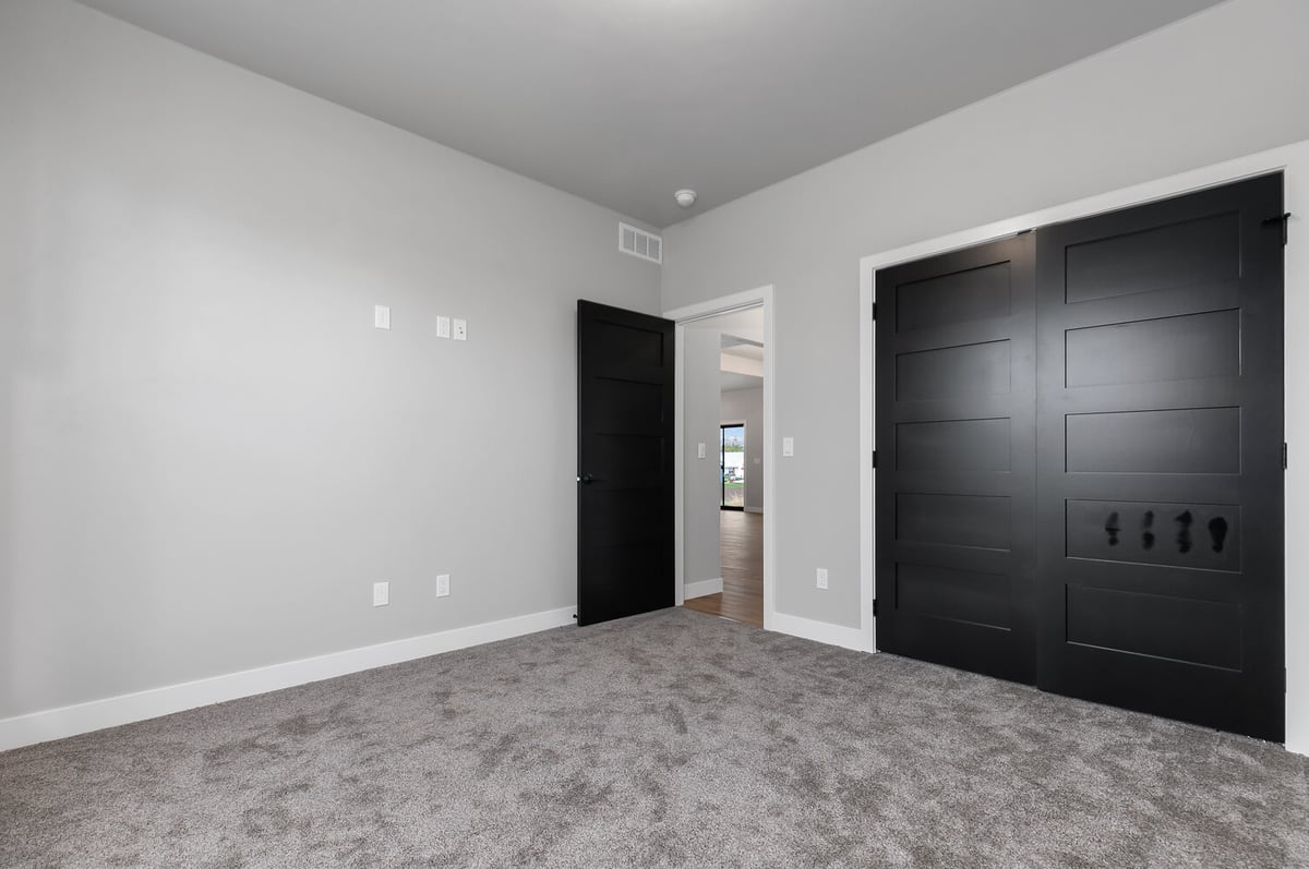 Carpeted bedroom with black double doors in custom home by Midwest Design Homes, Kaukauna WI