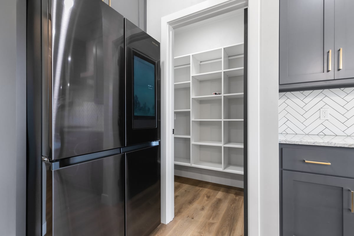 Close-up of modern refrigerator and walk-in pantry in Kaukauna custom home by Midwest