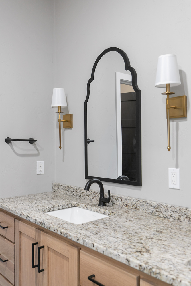 Granite bathroom vanity with gold sconces by Midwest Design Homes in Appleton Wisconsin