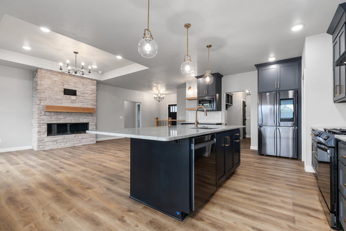 Kitchen island with sink and stone fireplace in custom home by Midwest Design Homes