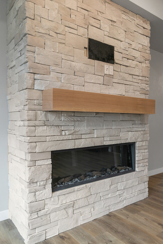 Stone fireplace and wood mantel in Kaukauna custom home by Midwest Design Homes