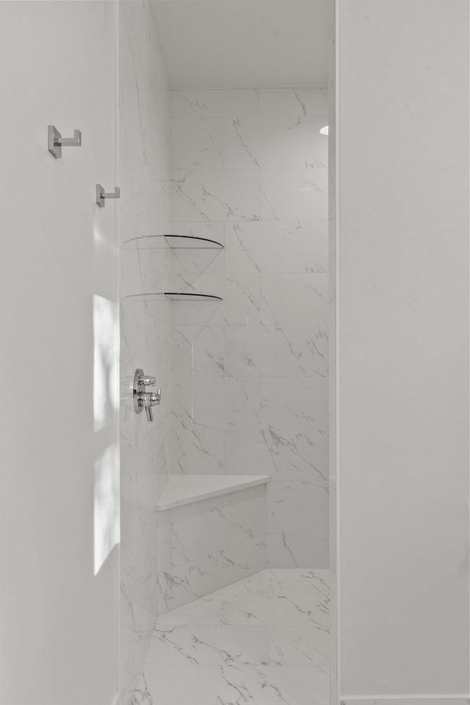 Bright marble shower with corner bench in Wisconsin custom home by Midwest Design Homes