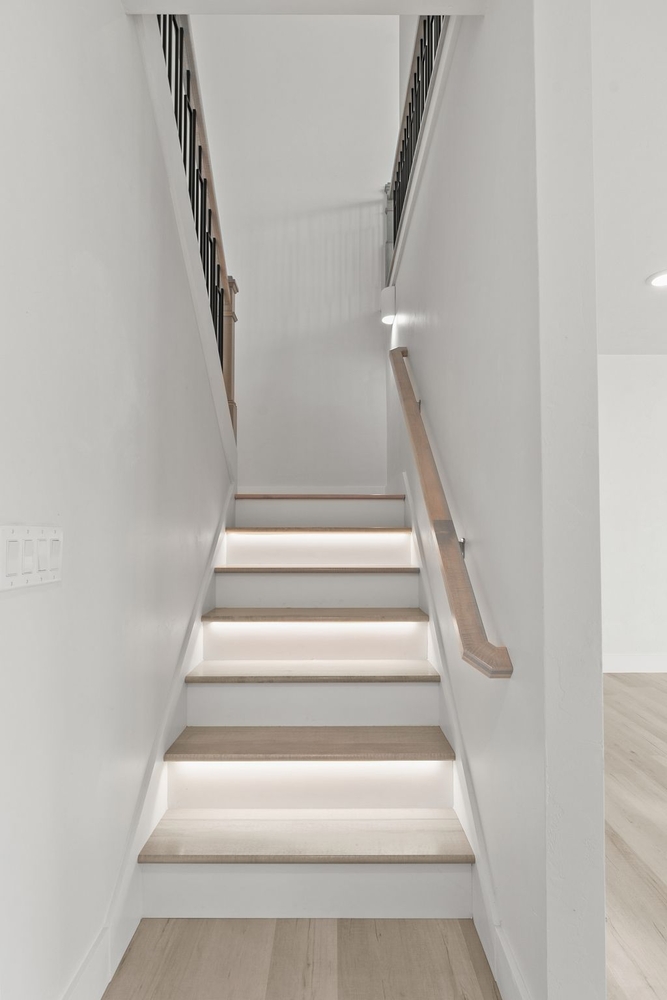Illuminated stairwell with wood handrail in custom home by Midwest Design Homes