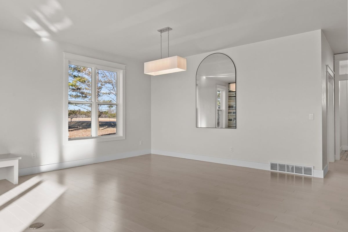 Minimalist living space with large window and mirror in Kaukauna by Midwest Design Homes