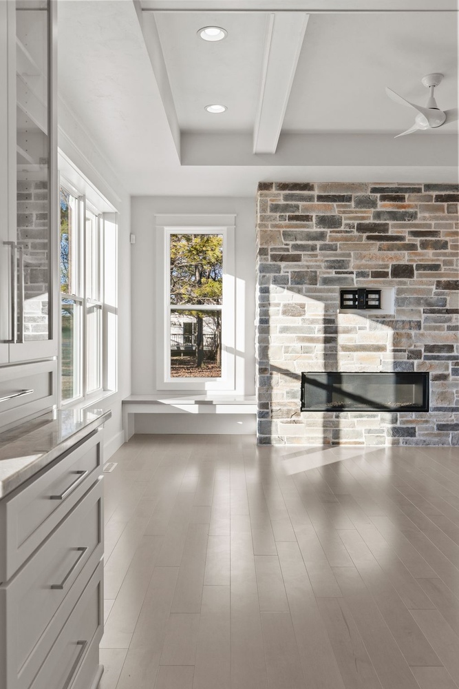 Stone fireplace and tall windows in custom home living room by Midwest Design Homes in WI
