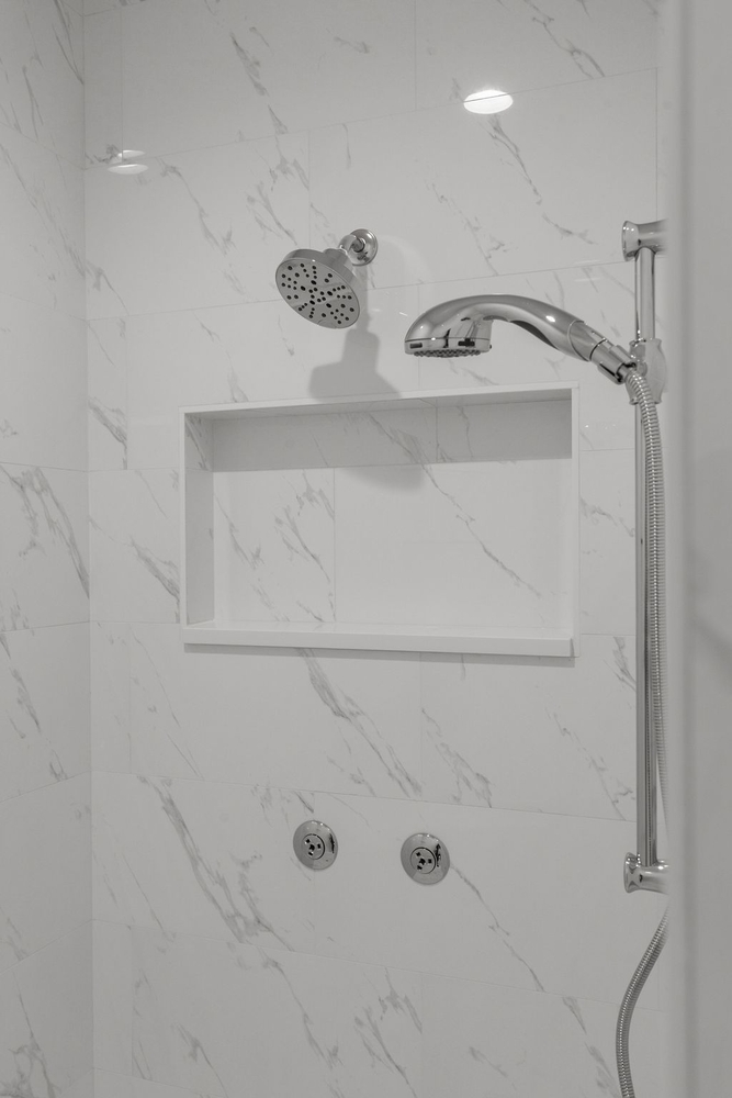 White marble shower with chrome fixtures in custom home by Midwest Design Homes, WI