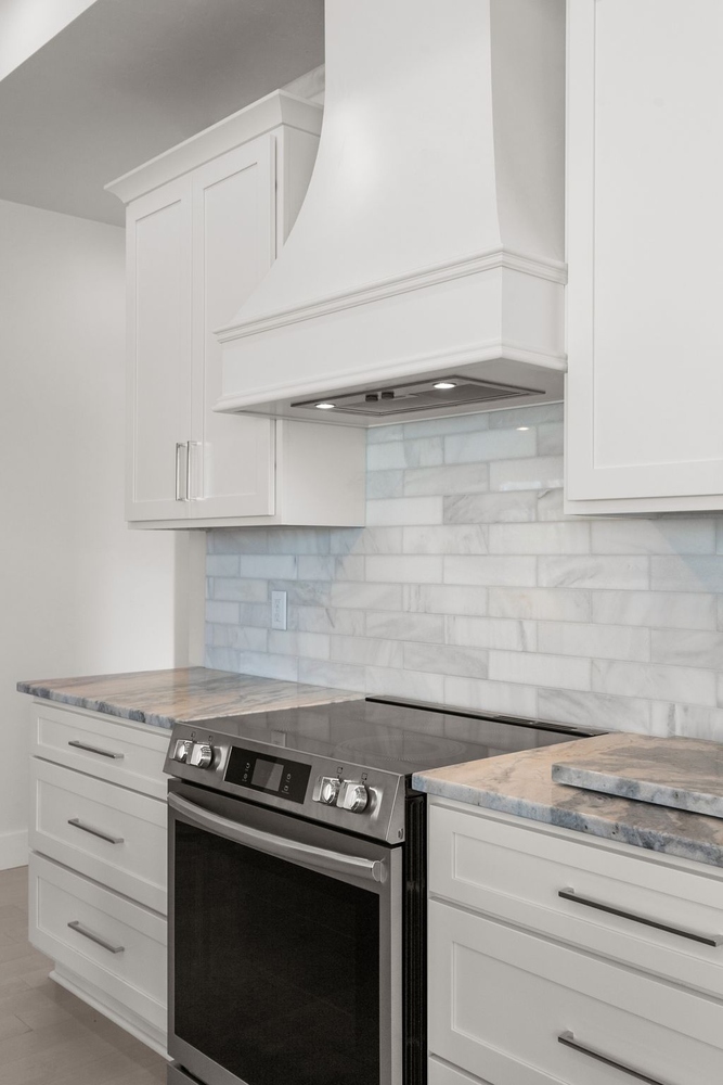 White range hood and marble backsplash in custom kitchen by Midwest Design Homes in Kaukauna