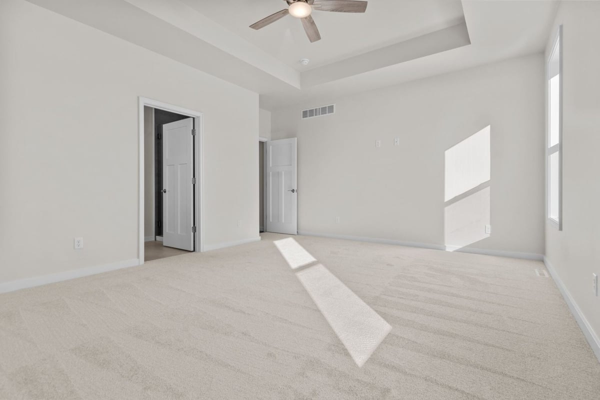 Bright primary bedroom with tray ceiling by Midwest Design Homes in Neenah, Wisconsin