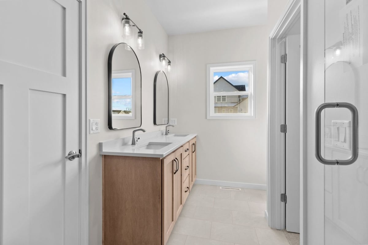 Custom bath with dual sinks and arched mirrors by Midwest Design Homes in Fremont, WI