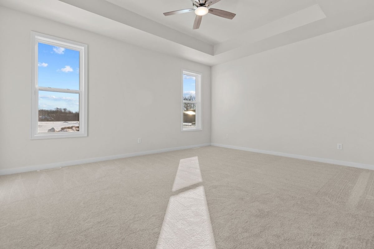 Primary bedroom with tray ceiling and large windows by Midwest Design Homes, Appleton, WI