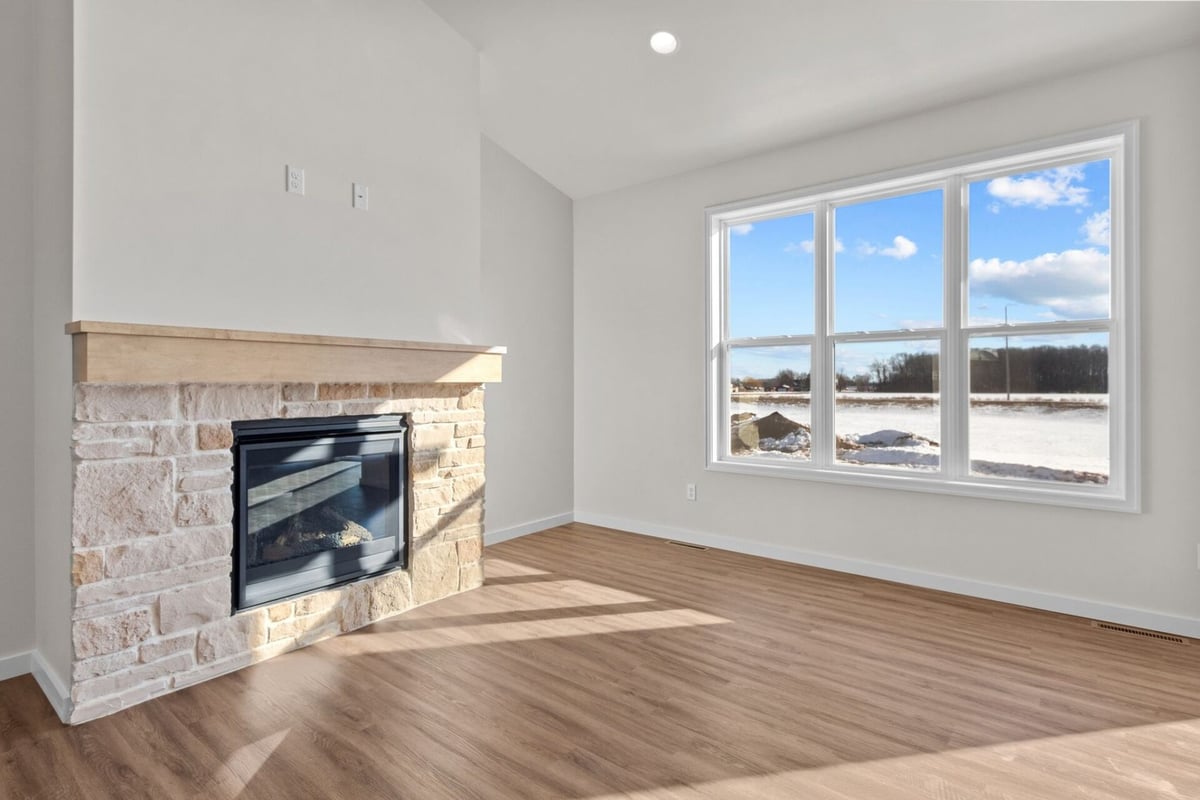 Stone fireplace and wood floors in living room by Midwest Design Homes, Harrison, WI
