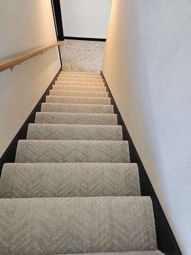 Carpeted staircase with wood handrail by Midwest Design Homes in Kaukauna, Wisconsin