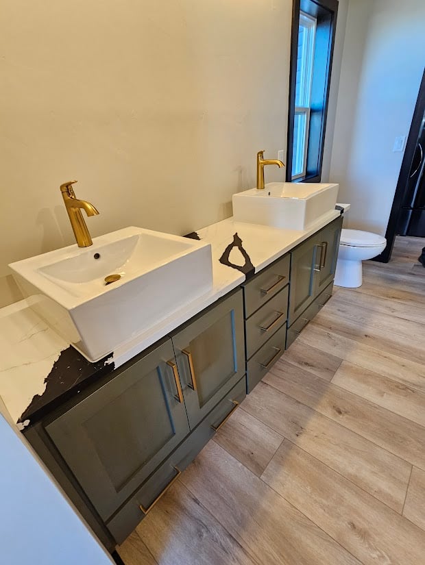 Double vanity with gold faucets and green cabinets by Midwest Design Homes, WI