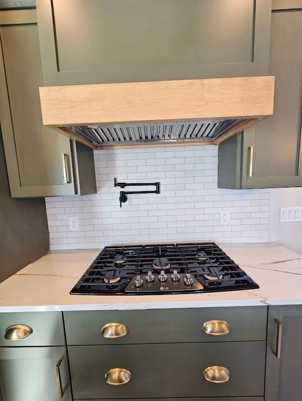 Gas cooktop and wood range hood in custom kitchen by Midwest Design Homes, WI