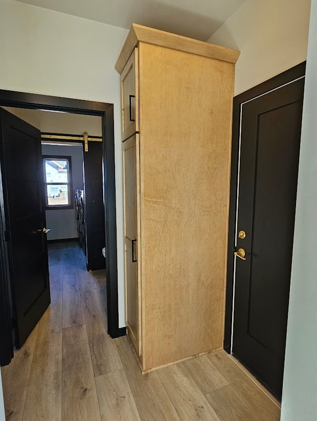 Hallway with light wood cabinet and black doors by Midwest Design Homes in Wisconsin