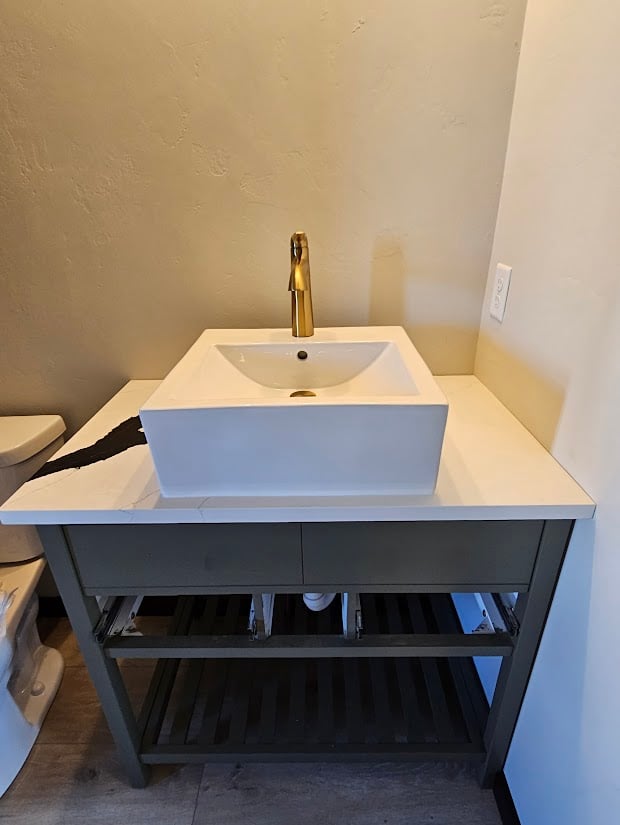 Single vanity with open shelf design and gold faucet by Midwest Design Homes, WI