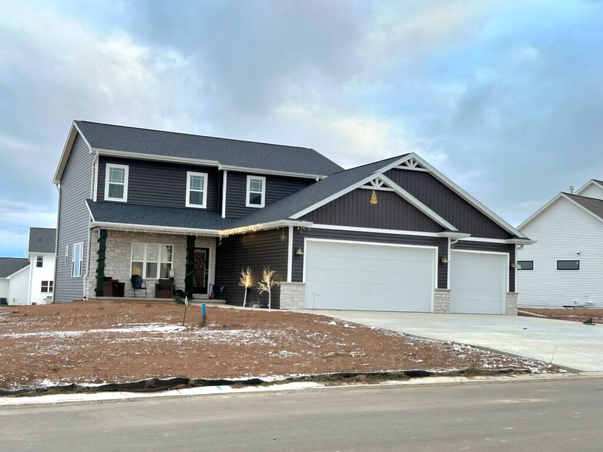 Two-story custom home with dark siding and white garage by Midwest Design Homes, WI