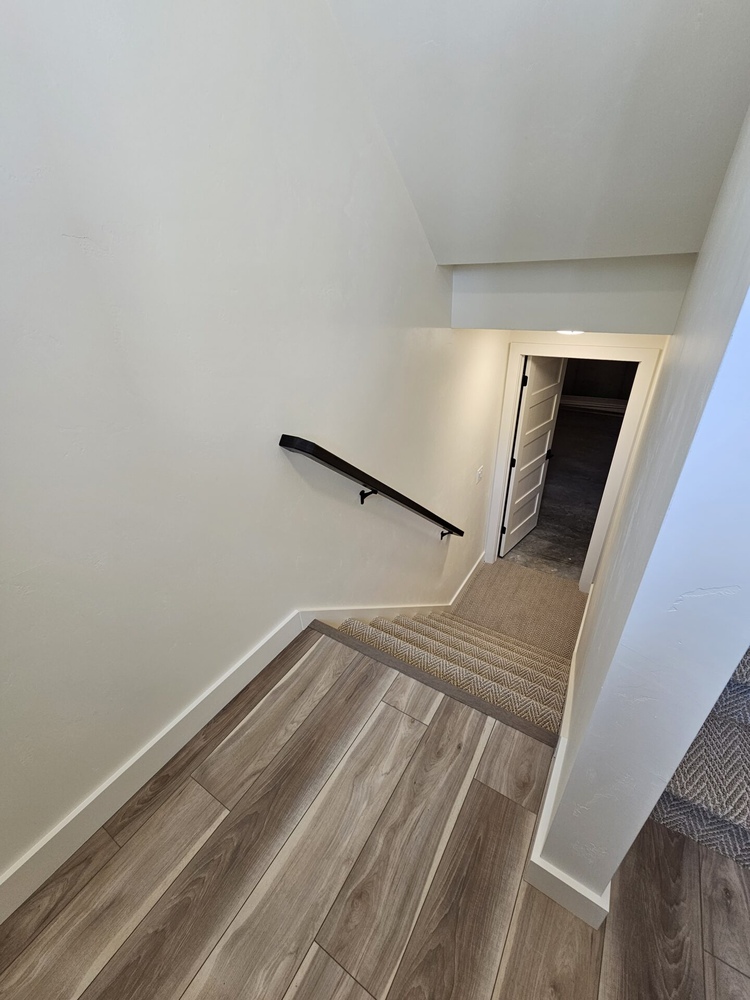 Basement stairway with wood flooring in Kaukauna custom home by Midwest Design Homes