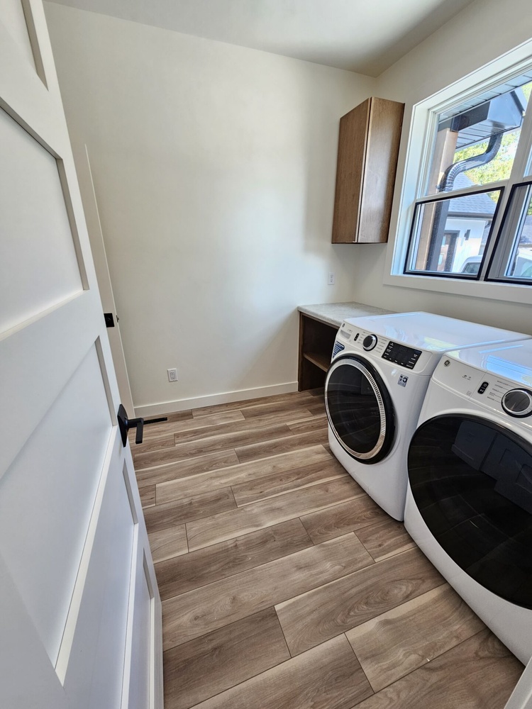 Bright laundry room with natural light and cabinet storage by Midwest Design Homes in Kaukauna