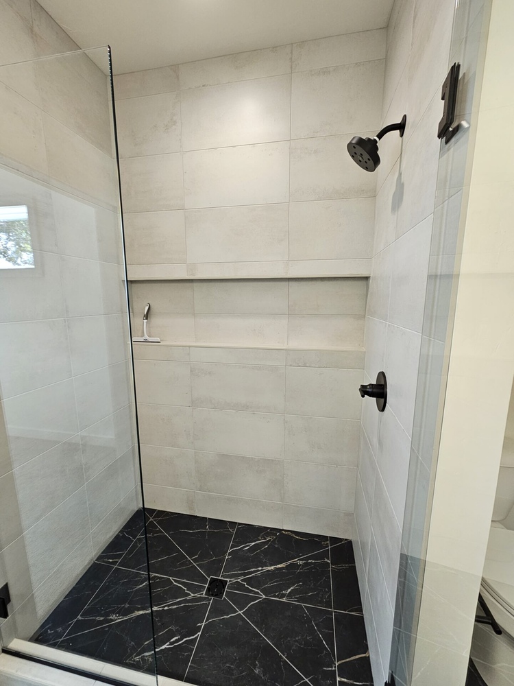 Contemporary shower with black tile and matte black hardware in Kaukauna by Midwest Design Homes