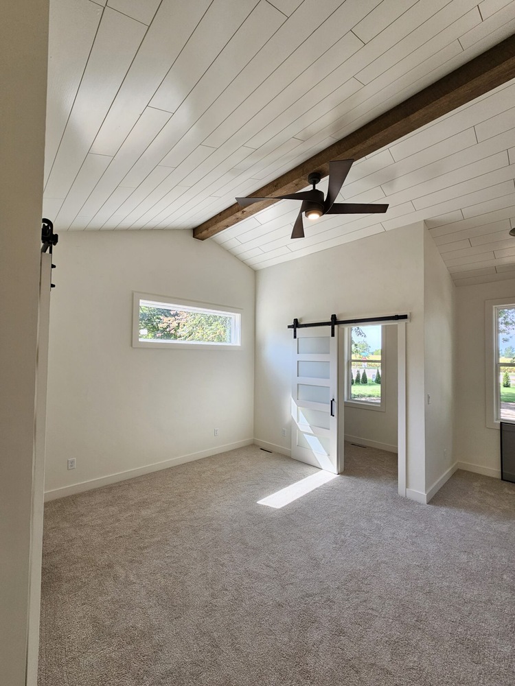 Custom bedroom with wood beam ceiling and large windows by Midwest Design Homes in Kaukauna