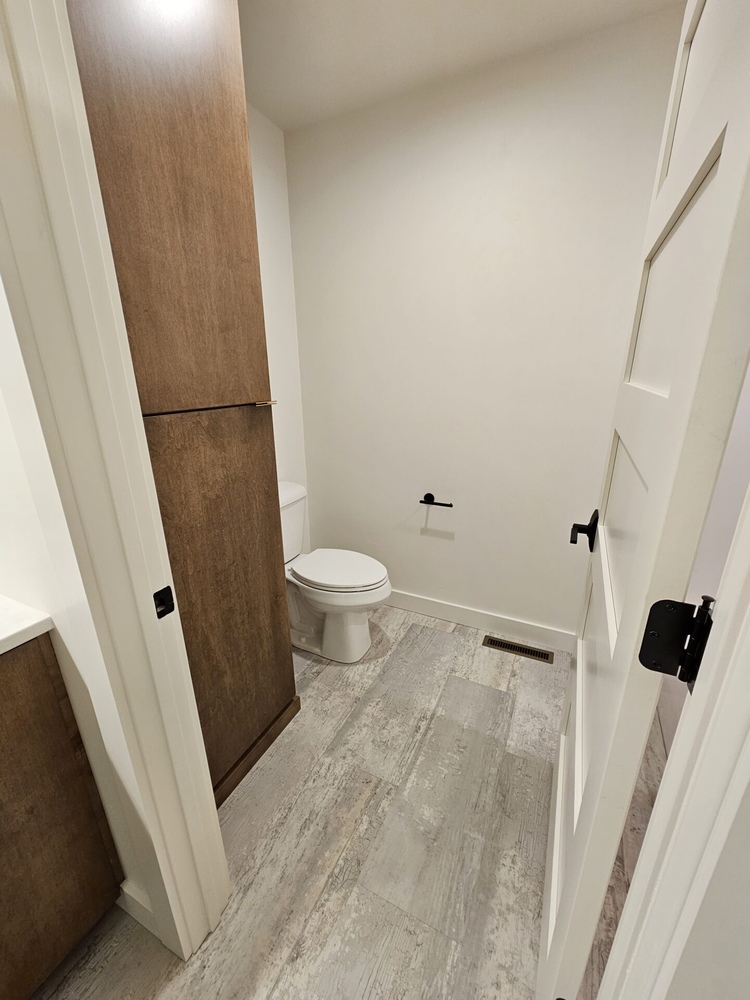Half bathroom with wood cabinetry and plank flooring by Midwest Design Homes in Kaukauna