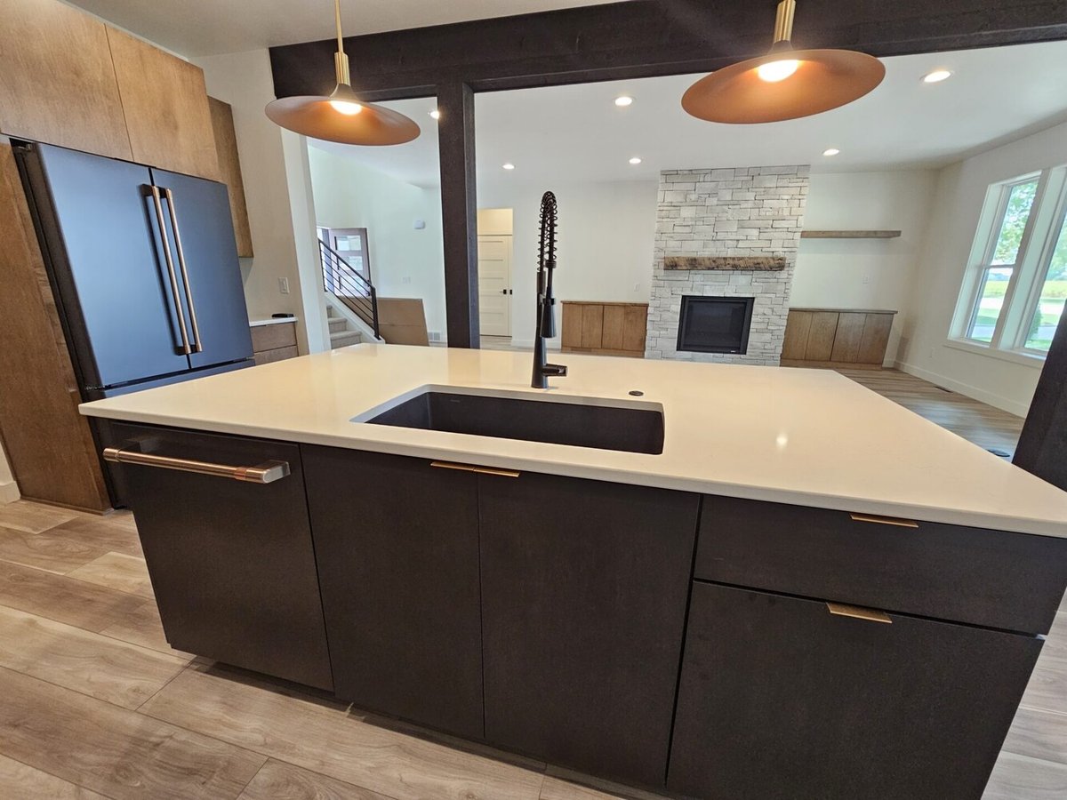 Kitchen island with black sink and view to living area by Midwest Design Homes in Kaukauna