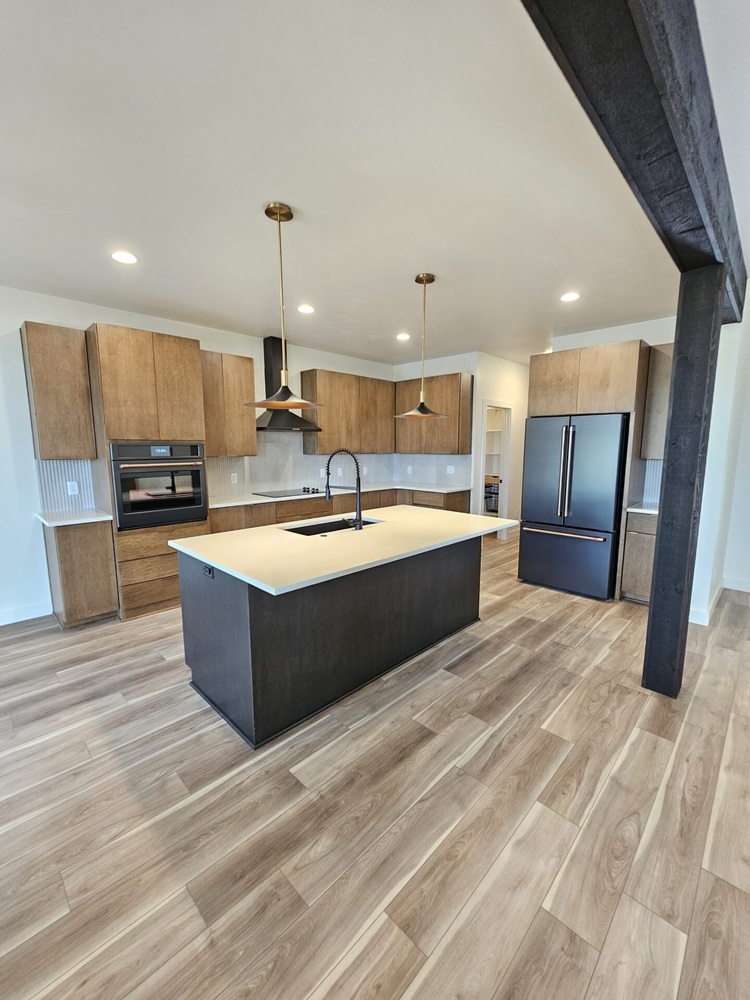 Kitchen with black island and wood cabinetry in Kaukauna home by Midwest Design Homes