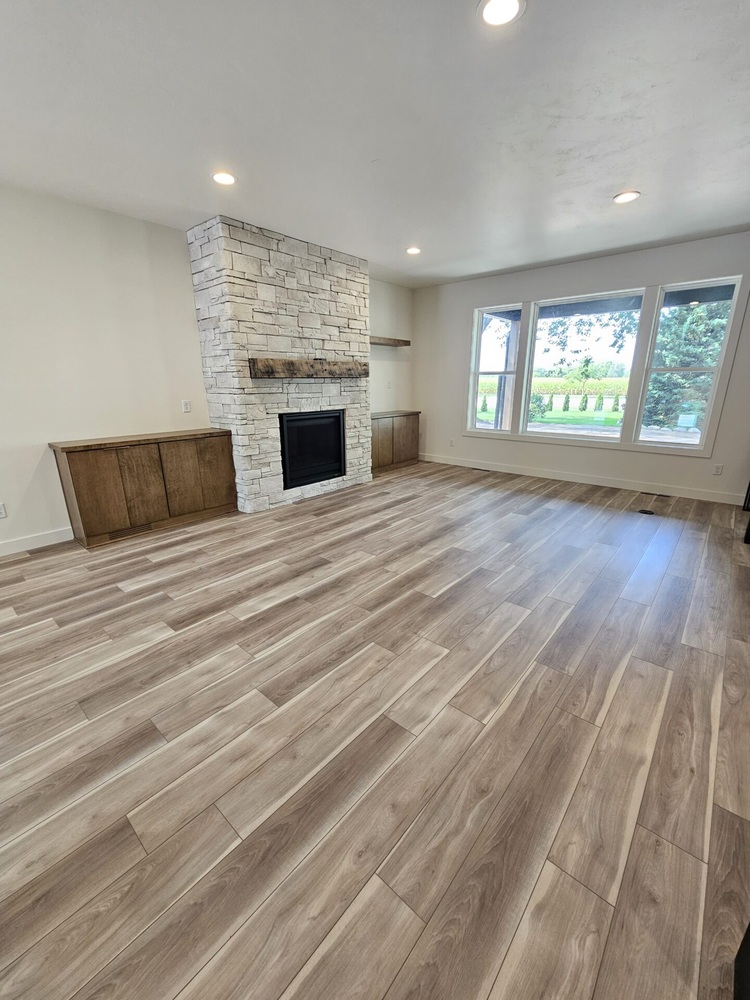 Living room with stone fireplace and large windows in Kaukauna by Midwest Design Homes