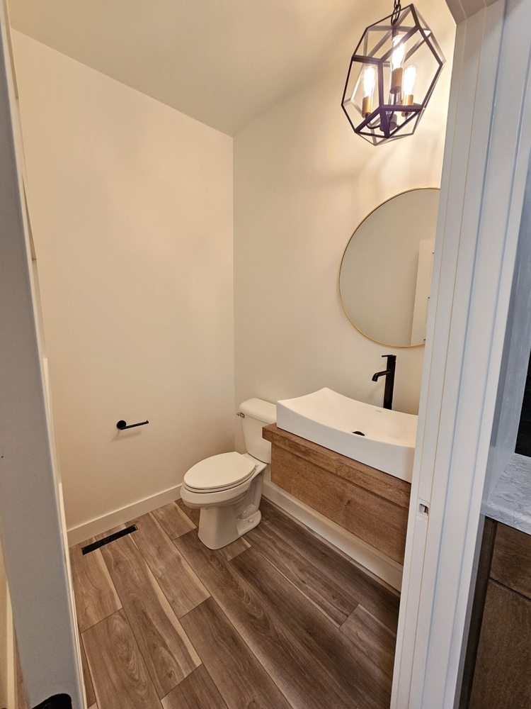 Modern powder room with wood vanity and unique light fixture in Kaukauna by Midwest Design Homes
