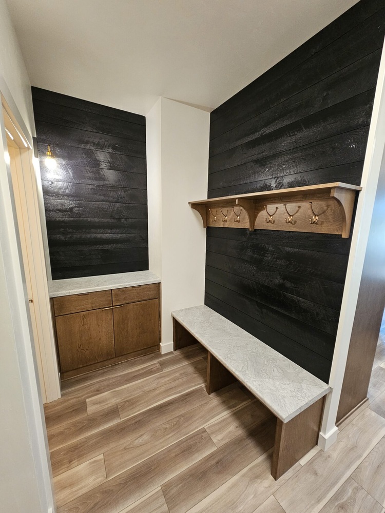 Mudroom with dark accent wall and storage bench by Midwest Design Homes in Kaukauna, WI