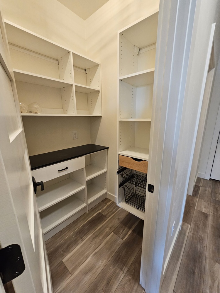 Pantry with white shelving and black countertop in Kaukauna custom home by Midwest Design Homes